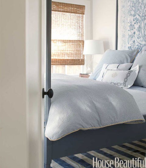 blue and white guest bedroom with a striped rug and wallcovering