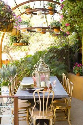 outdoor dining table with candle lantern and hanging potted plants