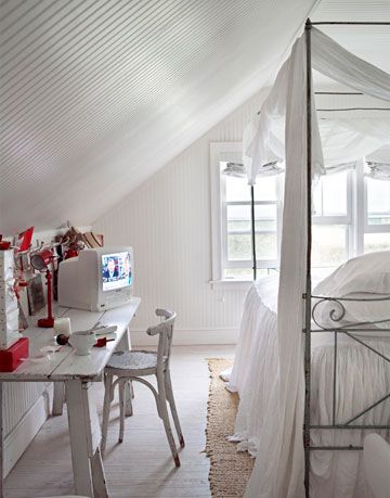 a white bed next to a white desk with a white tv