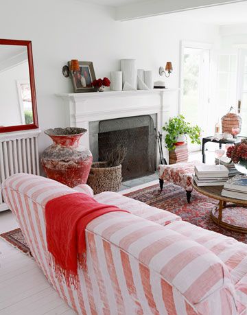 a red blanket draped over a striped sofa in front of a fireplace