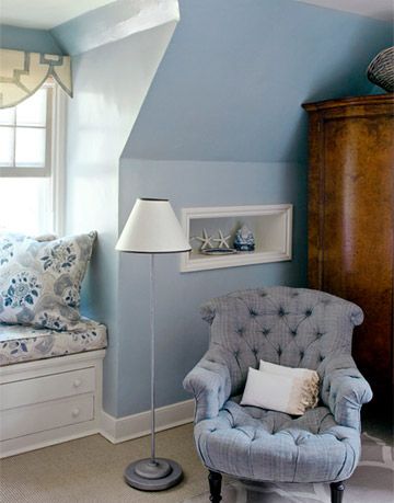 bedroom corner and window made over with blue paint an armoire a cushioned window seat a lamp and a blue armchair