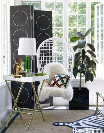 white hanging chair in front of a black screen in front of windows