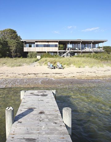 a dock on a beach in front of a modernist house
