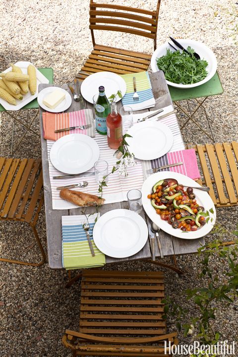 an outdoor table set with colorful striped italian linens