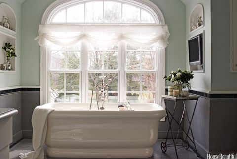 light green master bath with freestanding tub next to large window