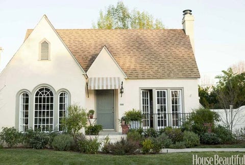 outside of cottage with a blue green door and a striped awning