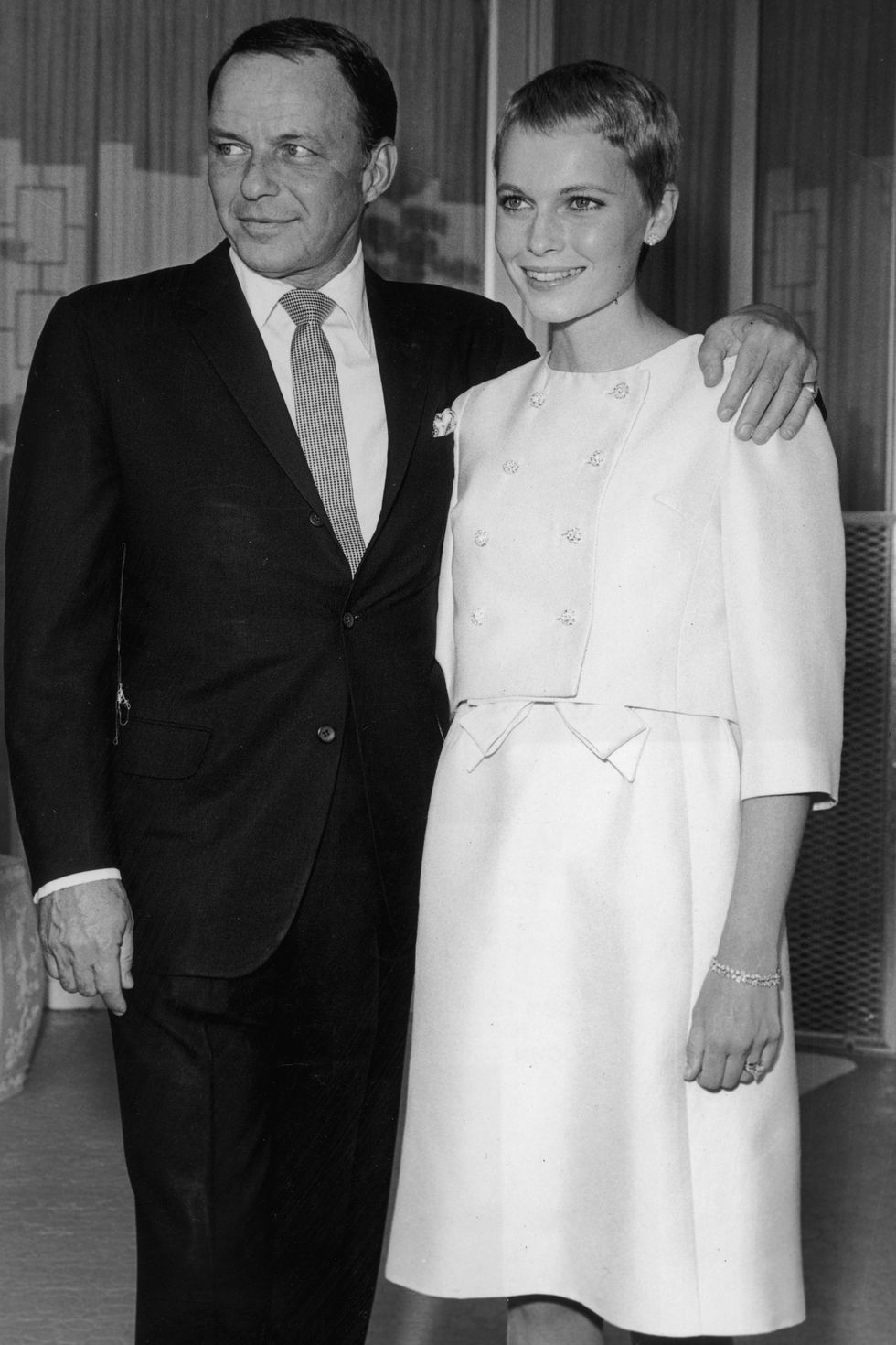 19th July 1966: American singer Frank Sinatra (1915 - 1998) stands with his arm around his third wife, actor Mia Farrow, during their private wedding in Las Vegas, Nevada. Sinatra wears a suit; Farrow has close-cropped hair and wears a pale-colored dress and matching cropped jacket. (Photo by Hulton Archive/Getty Images)
