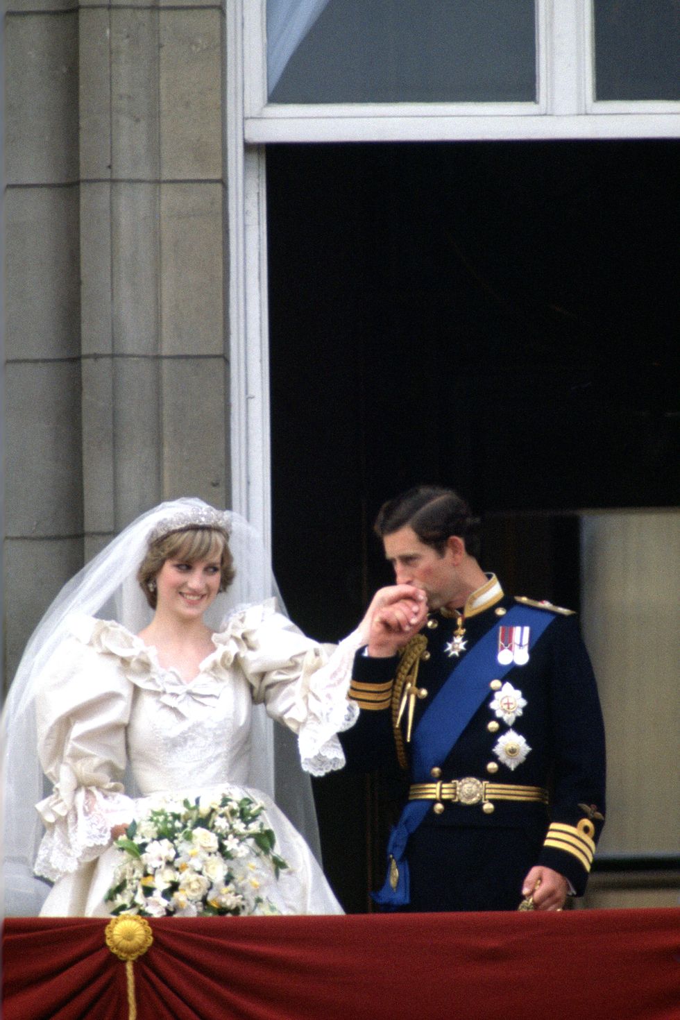 LONDON, UNITED KINGDOM - JULY 29: Prince Charles kisses the hand of his new bride, Princess Diana on the balcony of Buckingham Palace on their wedding day. (Photo by Tim Graham/Getty Images)