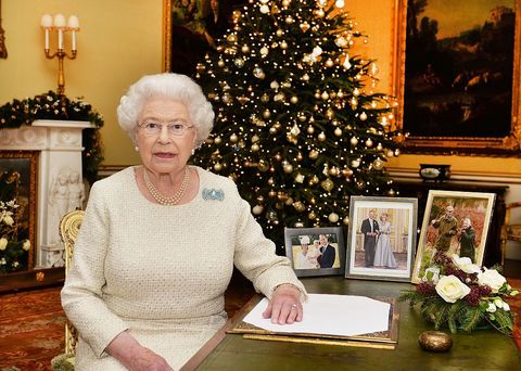 <p>The Queen is like every other mom and grandmother: Extremely proud of her family, as evident by the family photos on her desk. We also couldn't help but notice how her ensemble coordinates with the ivory flowers and tree ornaments.</p>