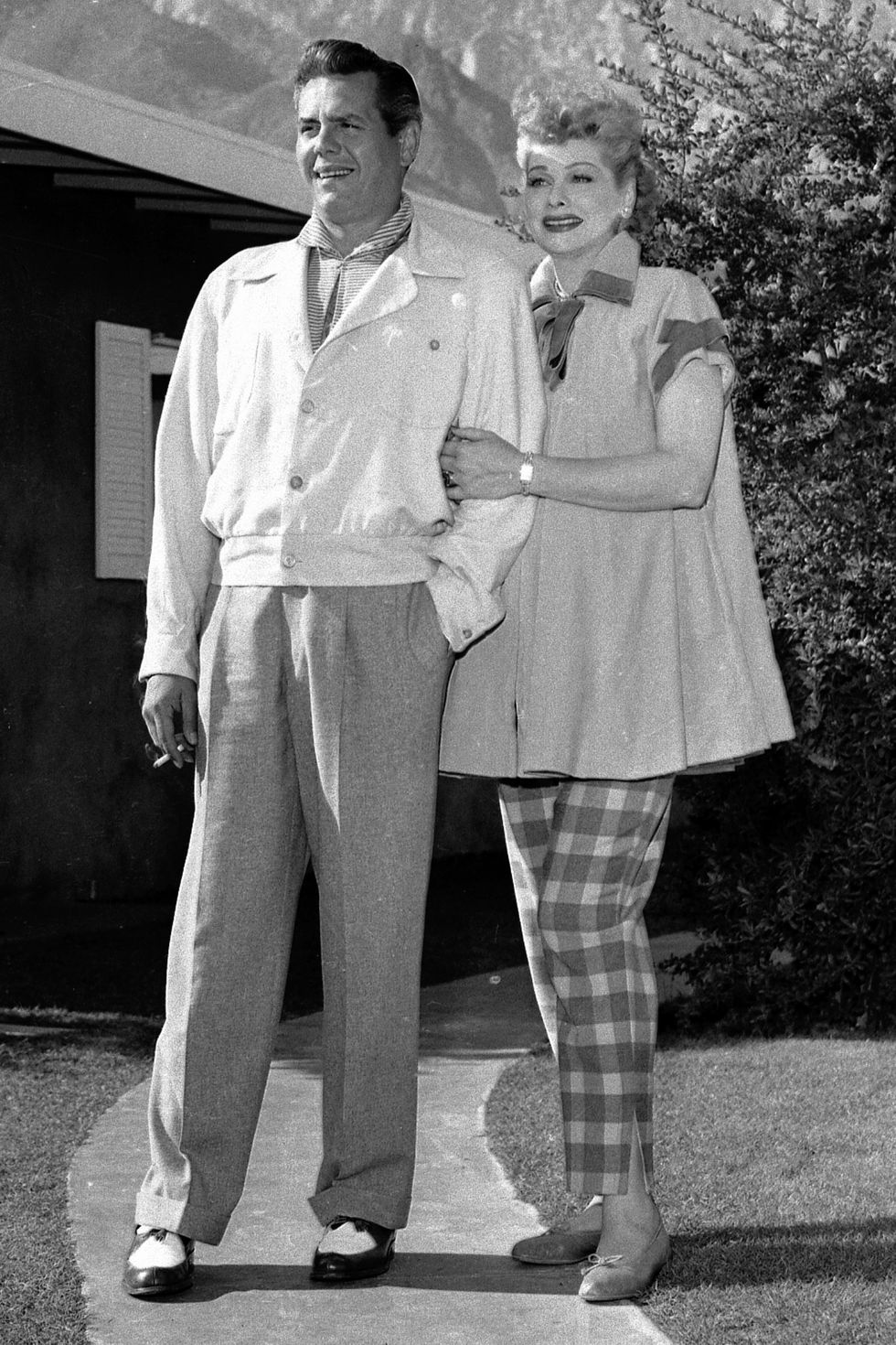 Cuban-born actor, comedian, and musician Desi Arnaz (1917 - 1986) stands with his pregnant wife, American actress and comedian Lucille Ball (1911 - 1989) as she lovingly holds on to his arm outside their home, 1953.  Coincidentally, the couples' son Desi Jr. would be born on the same day (January 19th) that the character of 'Little Ricky' on the television show 'I Love Lucy' was born. (Photo by CBS Photo Archive/Getty Images)