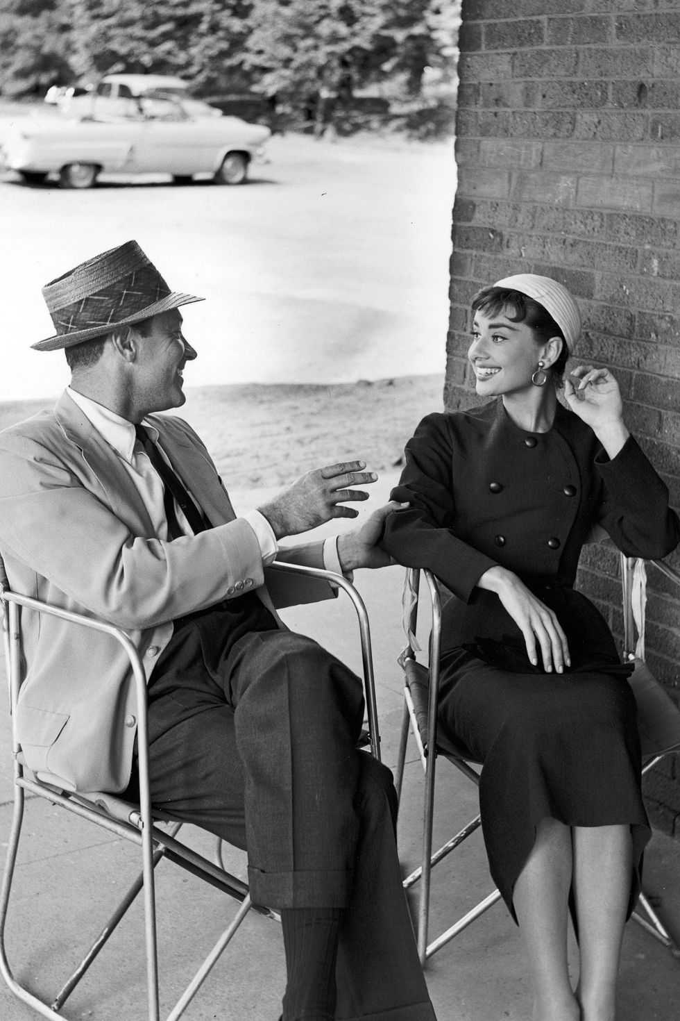 October 1953:  American actor William Holden (1918 - 1981) and Belgian-born actor Audrey Hepburn (1929 - 1993) sit next to each other in chairs talking, on the set of director Billy Wilder's film, 'Sabrina'. Both are wearing hats and smiling.  (Photo by Hulton Archive/Getty Images)