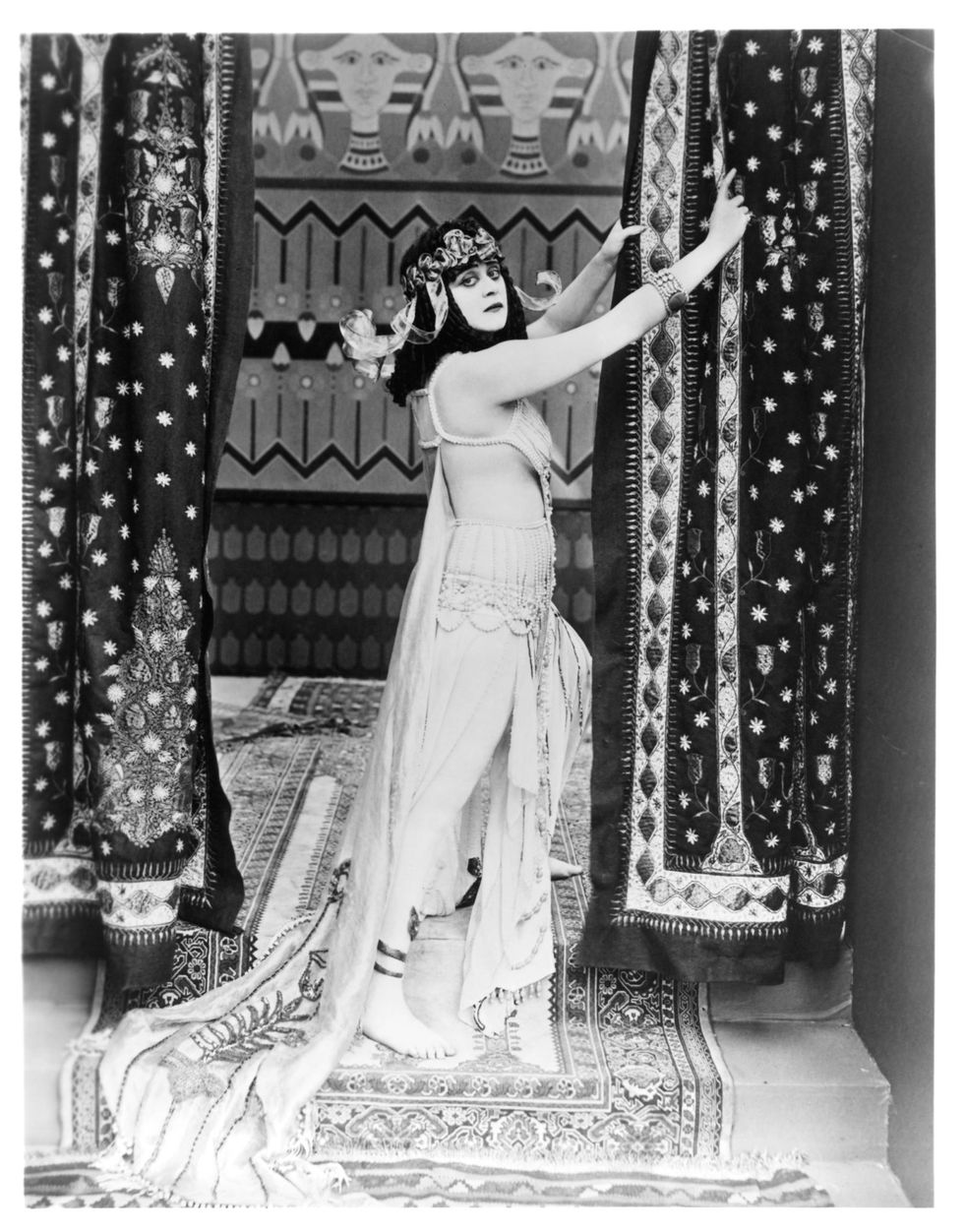 <p>De actrice Theda Bara werd één van Hollywoods eerste sekssymbolen en femme fatales toen ze in 1917 de rol van Cleopatra vertolkte in de gelijknamige film. De actrice droeg kostbare kostuums, gemaakt van slangenleer en edelstenen, die zorgvuldig rondom haar naakte lichaam gedrapeerd werden. Enkele scènes werden zelfs uit de film gecensureerd omdat er té veel bloot te zien zou zijn. Vele delen van de film zijn verloren gegaan, dus mocht je interesse gewekt zijn: helaas pindakaas.</p>