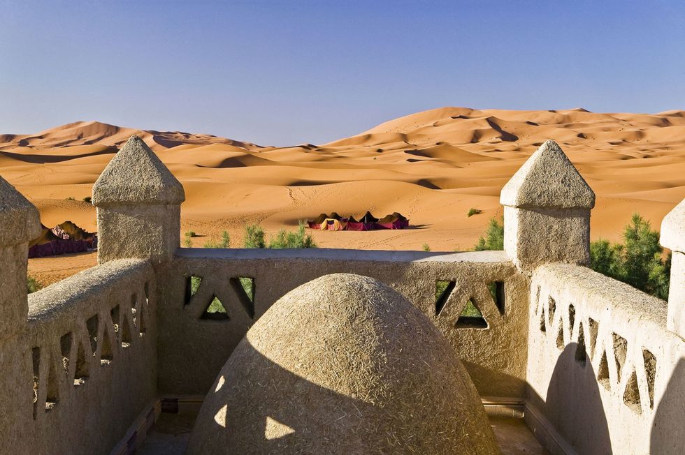 <p>Wie het liefst de hoge zandduinen in de woestijn opzoekt moet naar Merzouga, een dorpje aan de rand van de Sahara. Hier kun je vanuit je hotelkamer (bijvoorbeeld het <a href="http://www.ksar-merzouga.com/en/" target="_blank">Ksar hotel</a>) genieten van de zonsondergang. Of, doe 'ns gek en huur een traditionele tent in een Berberkamp. In dat laatste geval heb je ook 's nachts een mooi uitzicht wanneer je uitkijkt over de sterrenhemel. </p><p>Hoewel de kameel nog steeds het populairste vervoersmiddel is in Merzouga, heeft de Dakar Rally heel wat voeten in aarde gezet en kun je naast zo'n kameel ook een quad huren om de woestijn te verkennen. Rijdt er meteen even mee naar het zoutwatermeer Dayet Srji waar het hele jaar flamingo's, woestijnvossen, valken en gerbils te vinden zijn. </p>