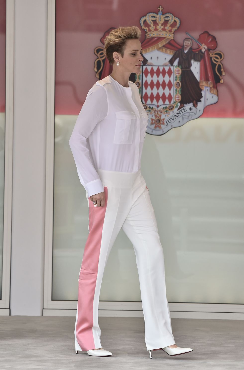 <p>In een wit broekpak met&nbsp;roze streep, bij de Grand Prix van Monaco.</p>