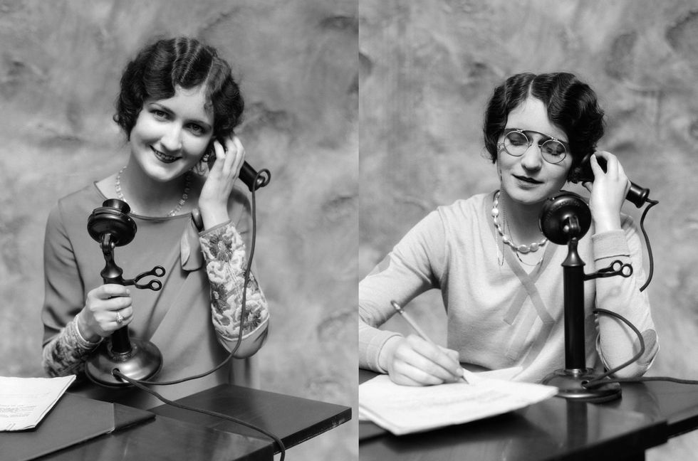1920s WOMAN WEARING PINCE-NEZ GLASSES SITTING AT DESK TALKING ON CANDLESTICK PHONE AND WRITING  (Photo by H. Armstrong Roberts/ClassicStock/Getty Images)