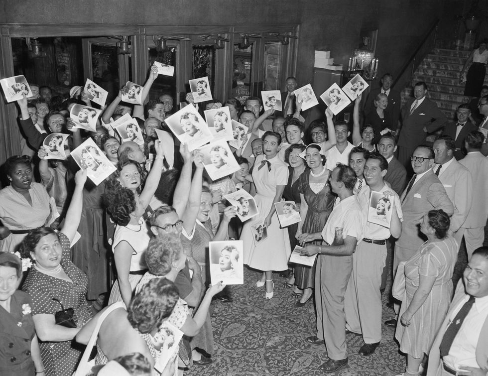 Actress Joan Crawford is surrounded by fans as she hands out autographed photographs of herself to early arrivals at the premiere of her film Sudden Fear, in the lobby of Loew's State Theatre in New York City.