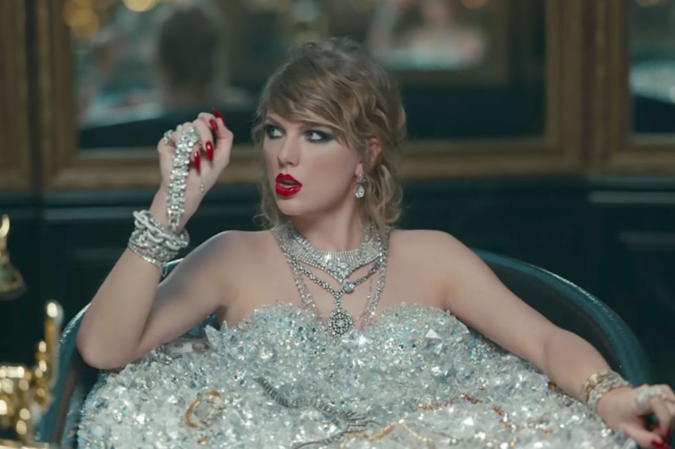 <p>While taking the world's most-painful bath to wash the dead off of her, Taylor rocks a super-smudgy cat eye, a loosely curled&nbsp;chignon, and some vinyl red lips to match her dangerously sharp nails.&nbsp;</p>