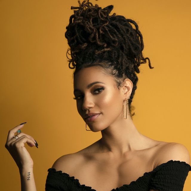 vick hope with her hair in a braided beehive, against an orange background