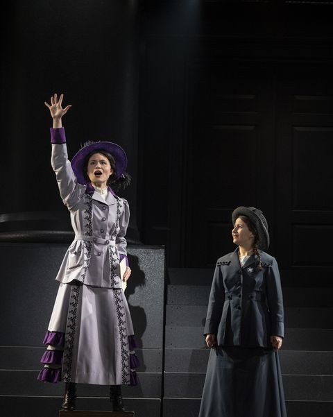 phillipa soo standing with her right hand raised while shaina taub looks at her