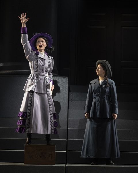 phillipa soo standing with her right hand raised while shaina taub looks at her