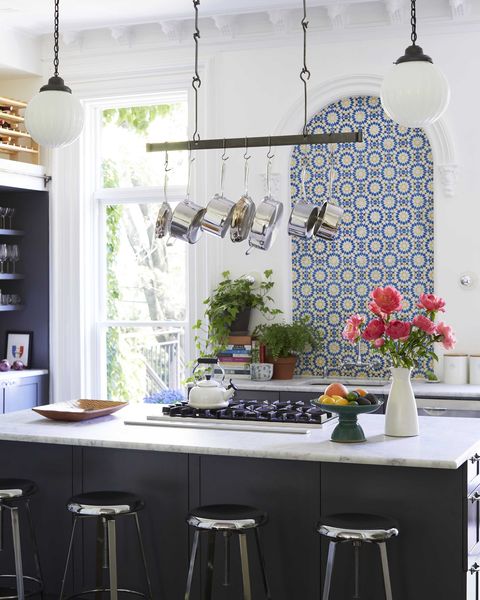 kitchen, black kitchen island, stainless steel bar stools, white marble countertops, black grill, blue and yellow tiles