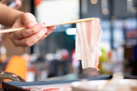 raw sliced bacon with chopsticks for sukiyaki or shabu shabu hot pot, fat meal