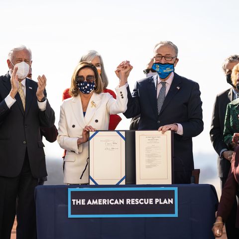 nancy pelosi and chuck schumer holding hands and celebrating the passage of the american rescue plan ac