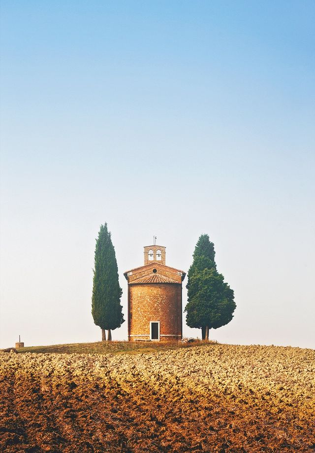 italy,tuscany,val d'orcia,church surrounded with cypress trees in mist