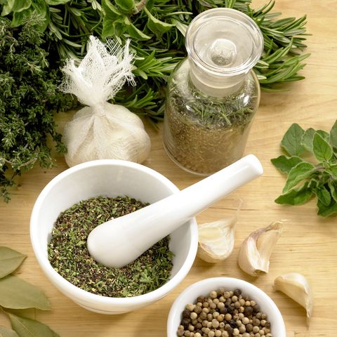 herbs in mortal and pestle with cheescloth bags