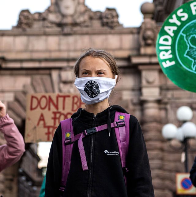 greta thunberg at a climate protest wearing a purple backpack and face mask