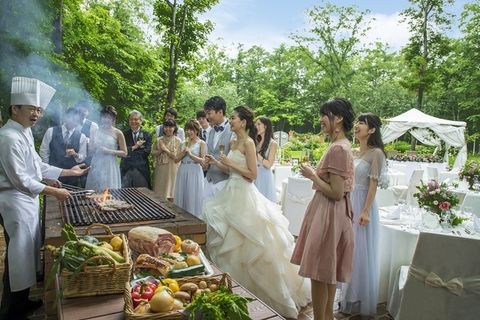 ニドムリゾートのフラワーガーデンで、炉を使ったビュッフェに新郎新婦とゲストが集まり、楽しく食事をしている様子の写真。