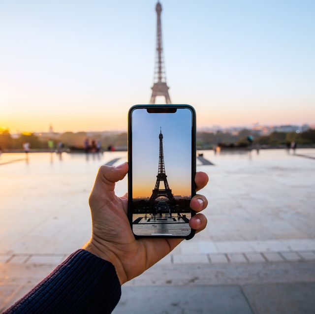 turista tomando una foto de la torre eiffel de parís con su móvil
