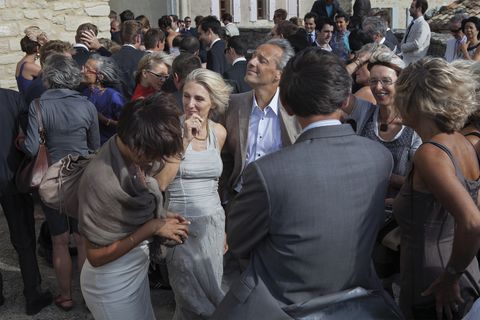 outside the saint romain church in crillon le brave, france, wedding guest enjoys being blasted by the mistral even as those around him hold onto their hats 24 july, 2010