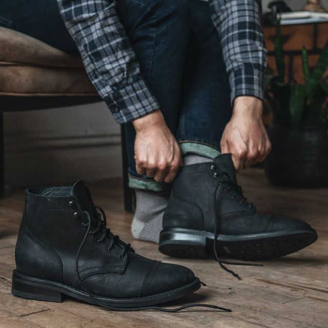 man putting on thursday boot co captain boot in black