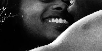black woman smiling and kissing partner while being intimate