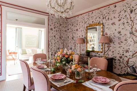 dining room, pink floral wallpaper, oval wooden table with pink velvet dining chairs, floral arraignment