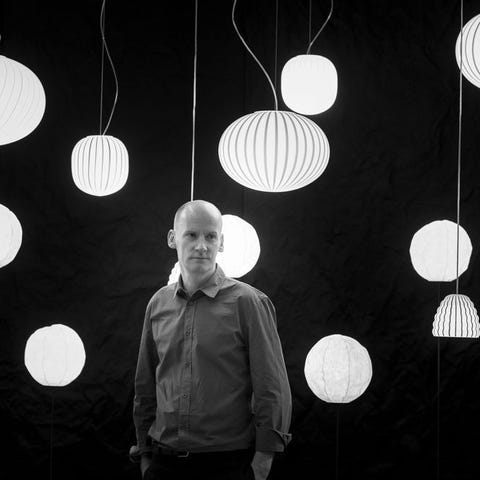 Black and white portrait of Sebastian Wrong of Established & Sons in front of pendant lights