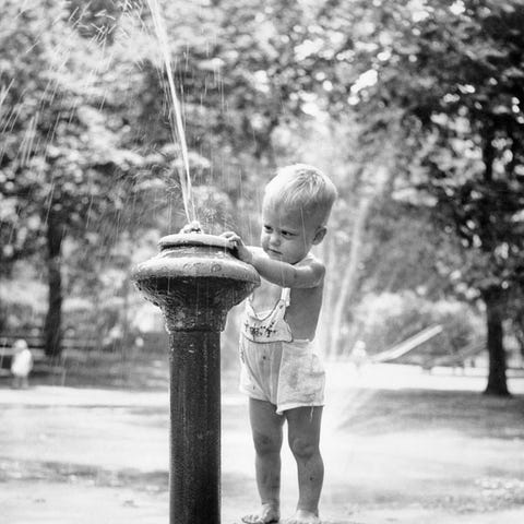 1950s little boy playing in water fountain