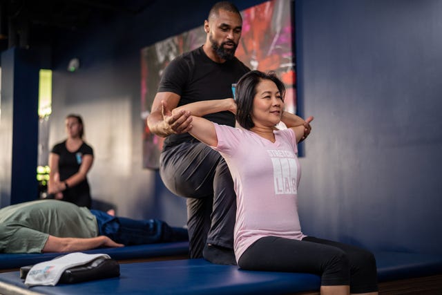 man helping a woman stretch in a class