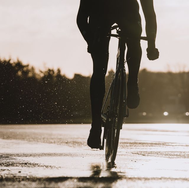 wielrenner in de regen die door een plas fietst