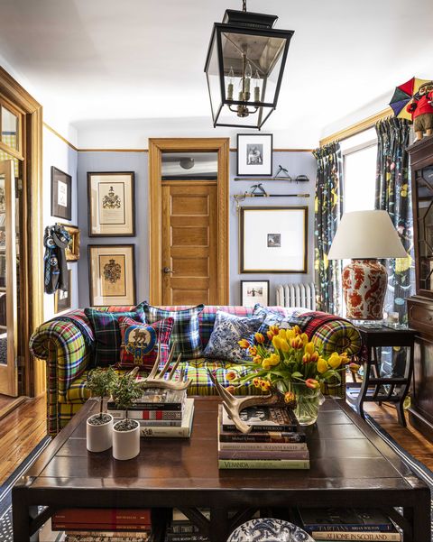 living room, vintage brown wood coffee table, coffee table books, wall art, pastel blue painted wall, tartan sofa