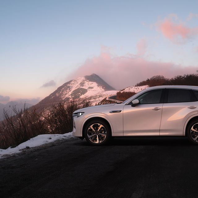 a car parked on a road with snow and mountains in the background