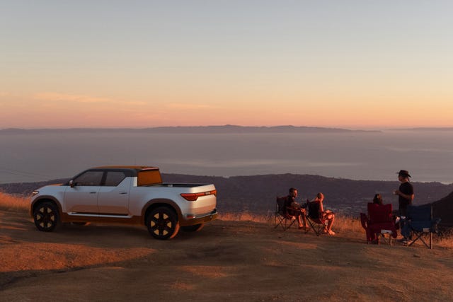 a truck parked on a dirt road with people sitting in chairs and a body of water in the