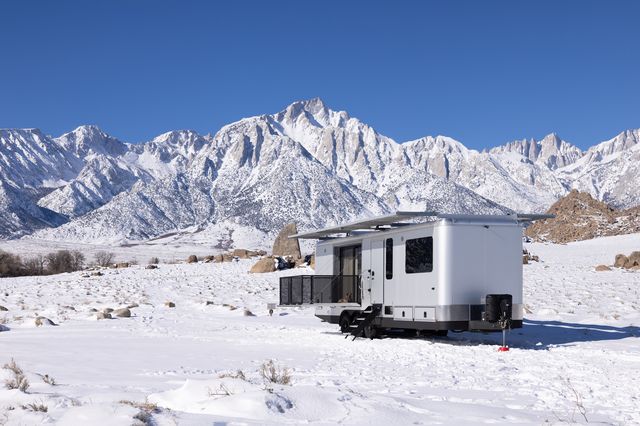 living vehicle trailer in the snow with mountains in the backdrop