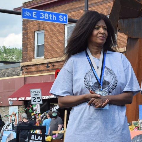 angela harrelson wearing a grey tshirt with george floyds face and appears to be on a podium