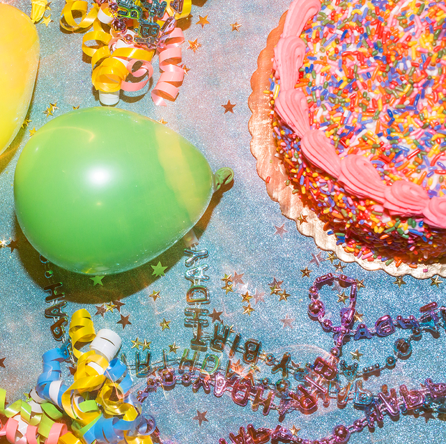 table top view of sprinkle birthday cake balloons and confetti