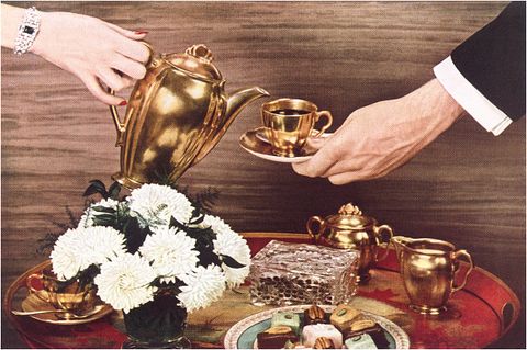 vintage photograph of womans hand pouring coffee from a gold pitcher into a gold cup and saucer held by a man’s hand above a tray with flowers and desserts in the 1960s  photo by found image holdingscorbis via getty images