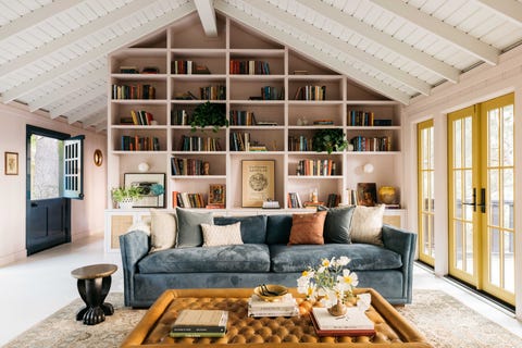 living room, sitting area with pink walls, blue sofa couch, brown leather ottoman, yellow french doors