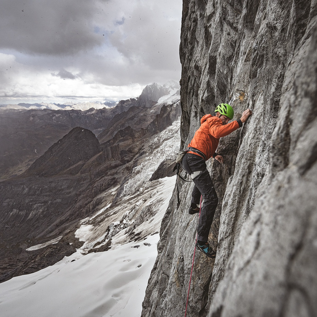 man in patagonia gear climbing a rock wall outdoors in winter