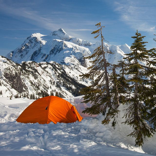 orange 4 season tent pitched in snowy mountains